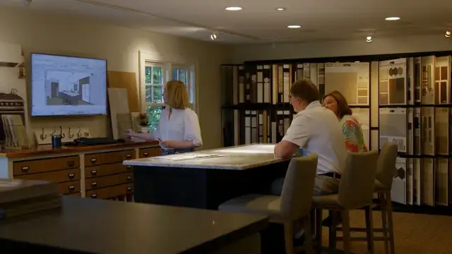 Clients meeting with a McDonald Remodeling designer at a table surrounded by cabinet, tile and flooring samples