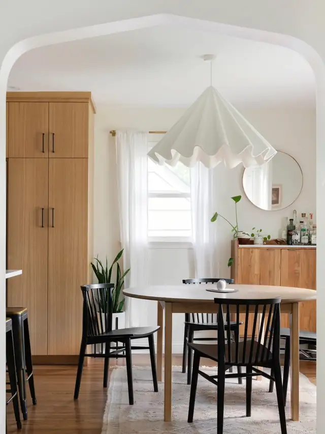 Dining nook by McDonald Remodeling with white oak cabinetry, a round table, black spindle chairs and a white pleated pendant