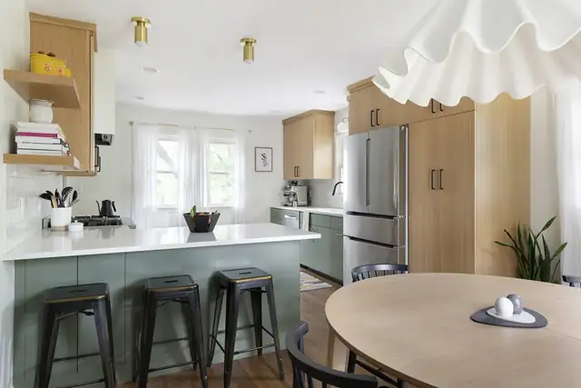 Mid-century Minneapolis kitchen remodel with a sage green island, wood cabinets, metal stools and a ruffled pendant
