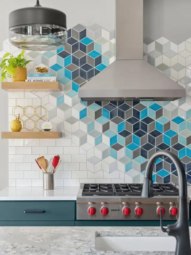 Kitchen backsplash of blue, gray and white geometric cube tile behind a stainless range hood, with floating wood shelves