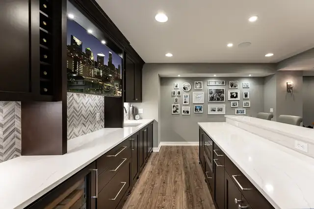 Mendota Heights lower-level bar with dark cabinets, white counters, built-in wine storage and a backlit city skyline photo