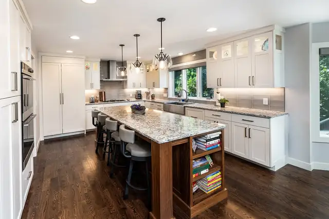 Eden Prairie whole-home remodel kitchen with white cabinets, a stone-topped wood island with built-in bookshelves and pendant lights